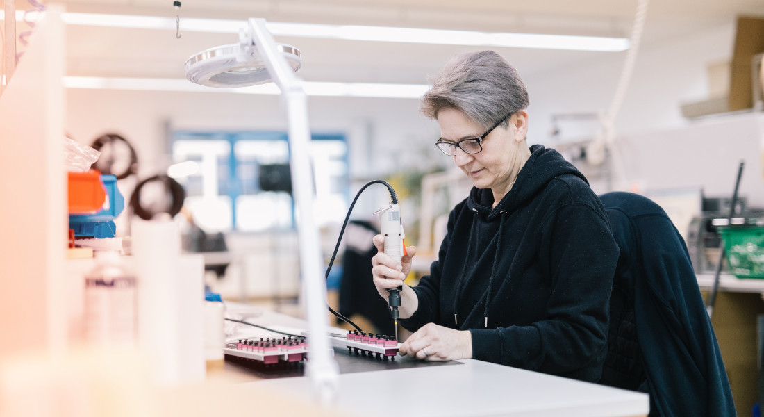 Frau bestückt Spleißbox, EFB-Elektronik